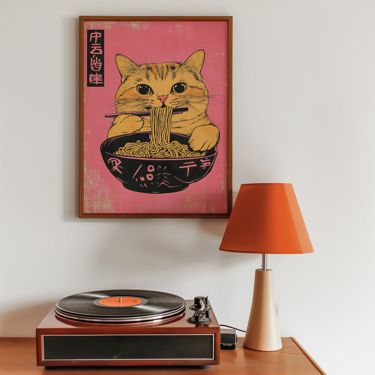Orange tabby cat slurping ramen print in a walnut frame above a sideboard with a record player