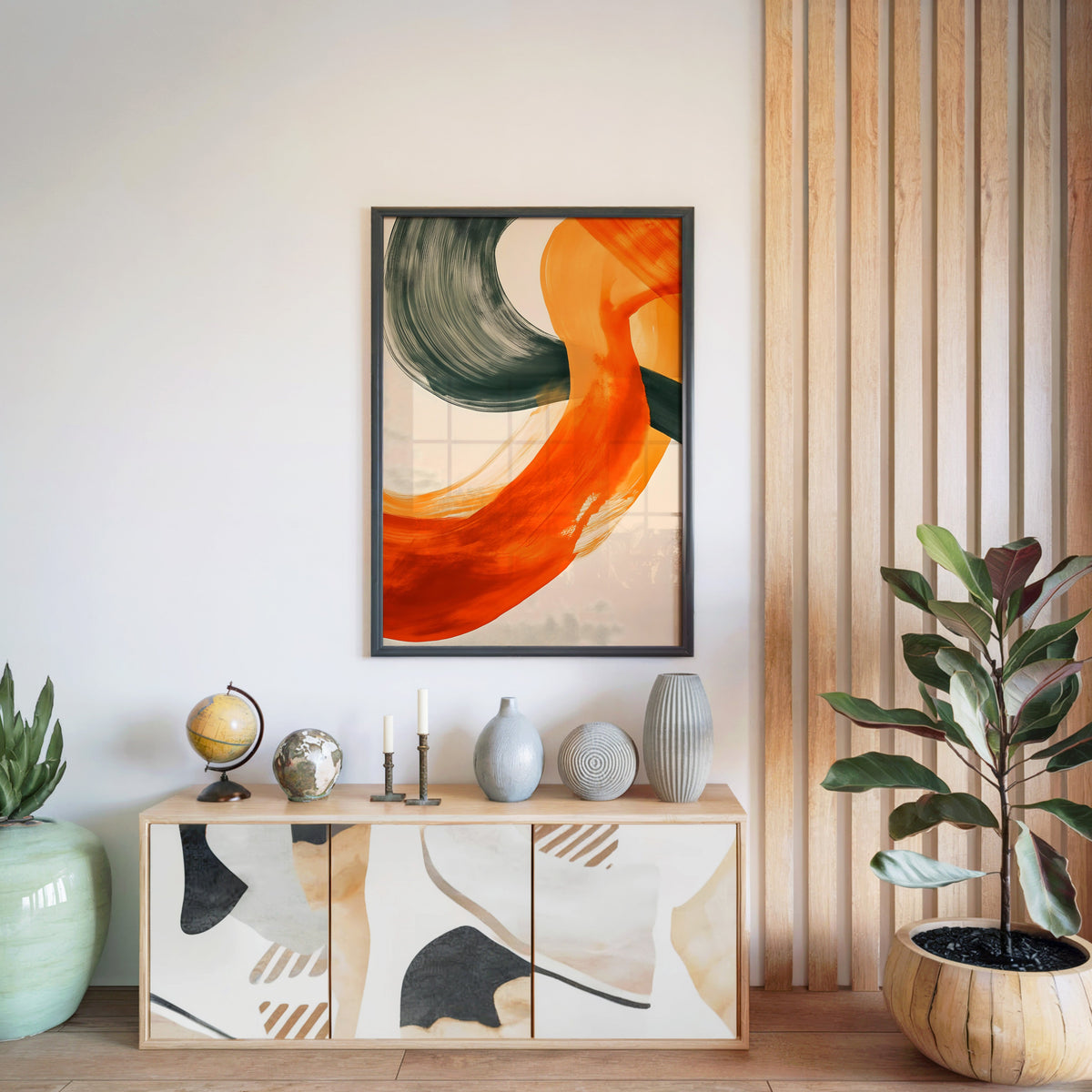 Orange and charcoal brushstroke abstract print in a black frame above a light wood sideboard by a wood slat wall