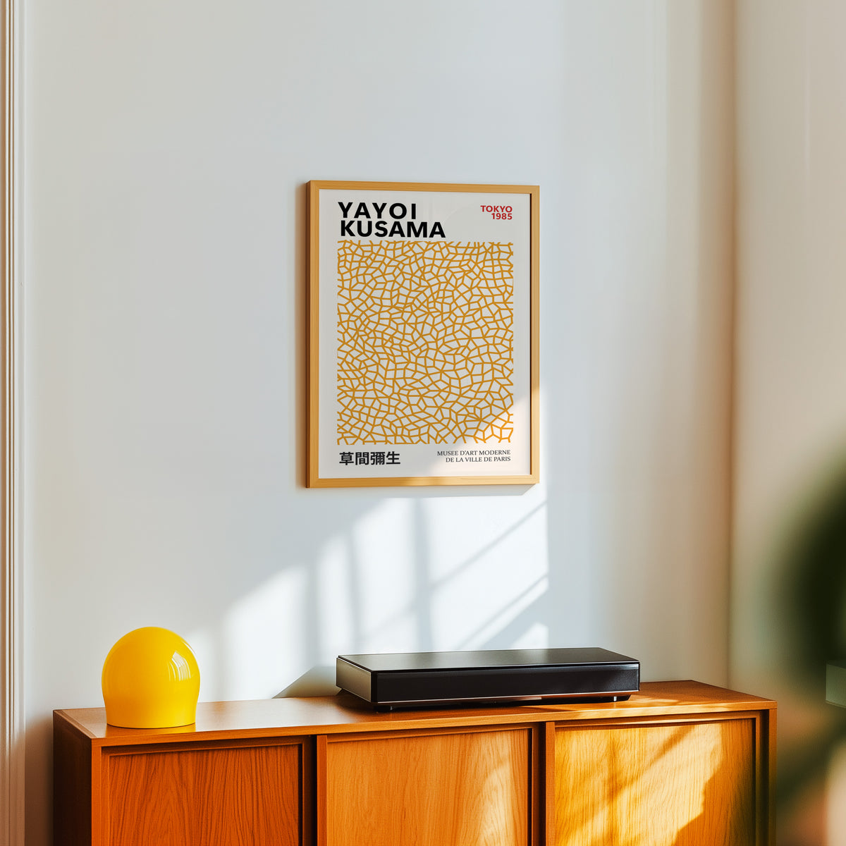 Yayoi Kusama inspired orange net pattern print above a sideboard with a yellow lamp