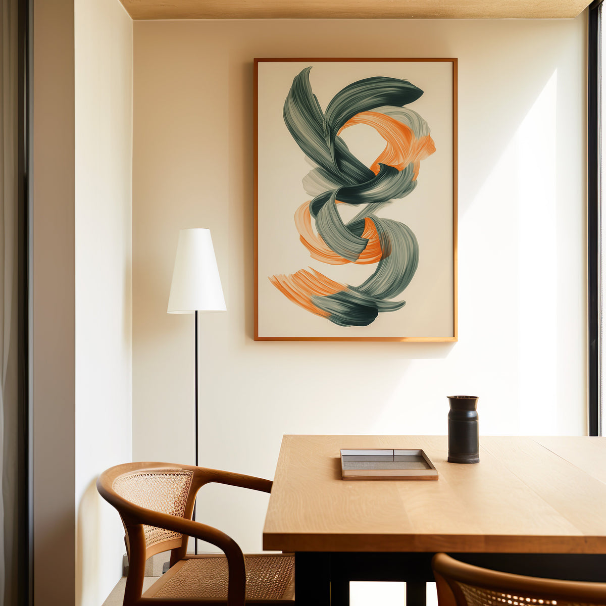 Orange and green brushstroke knot abstract print in a slim oak frame above a dining table with a cane-back chair