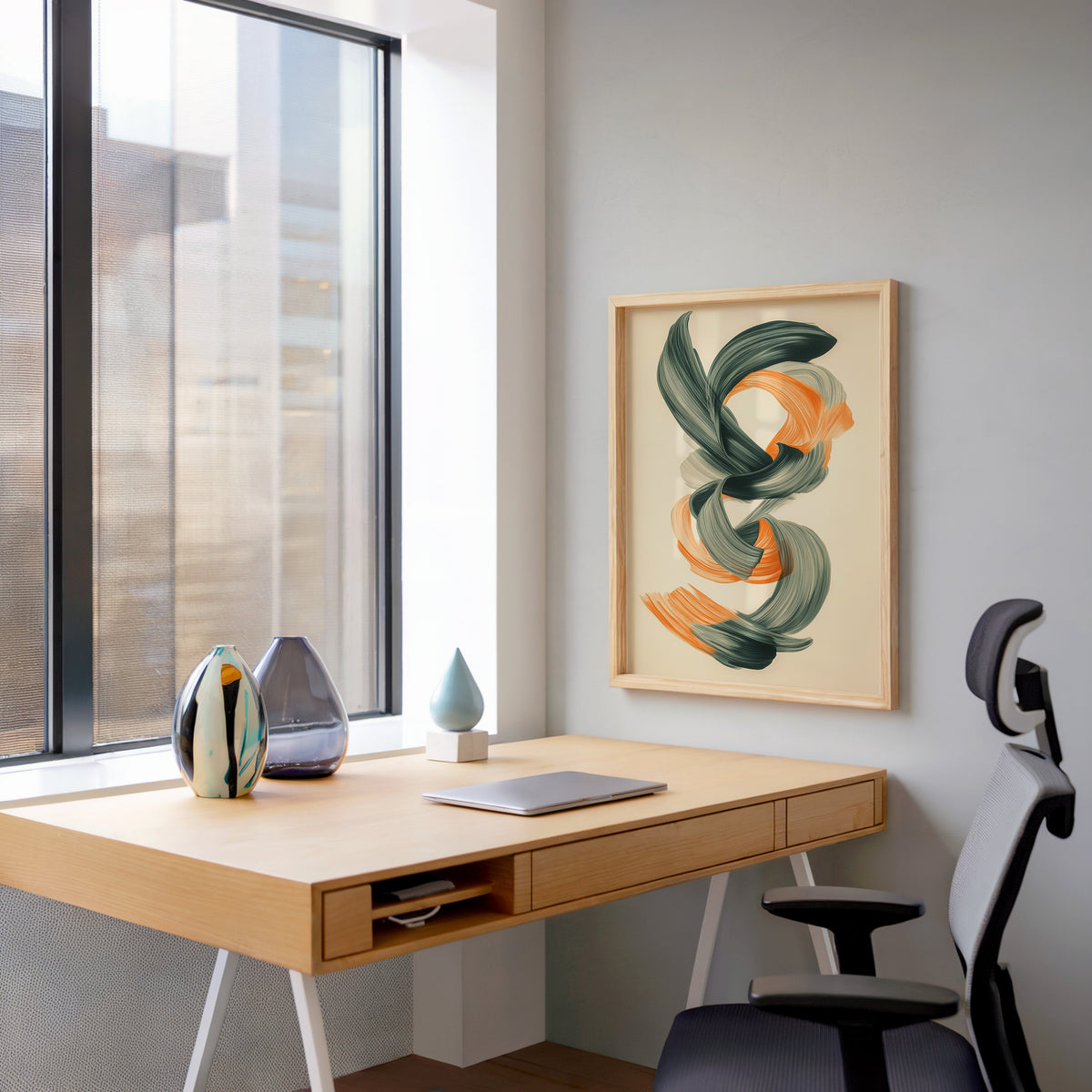 Orange and green brushstroke knot abstract print in a pale wood frame above a home office desk by a tall window
