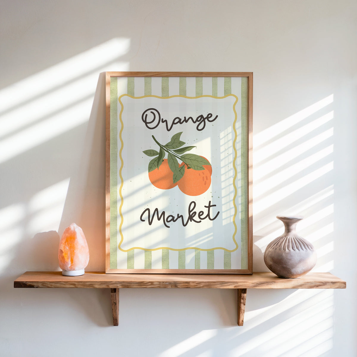 Orange Market print in an oak frame on a live-edge shelf beside a salt lamp