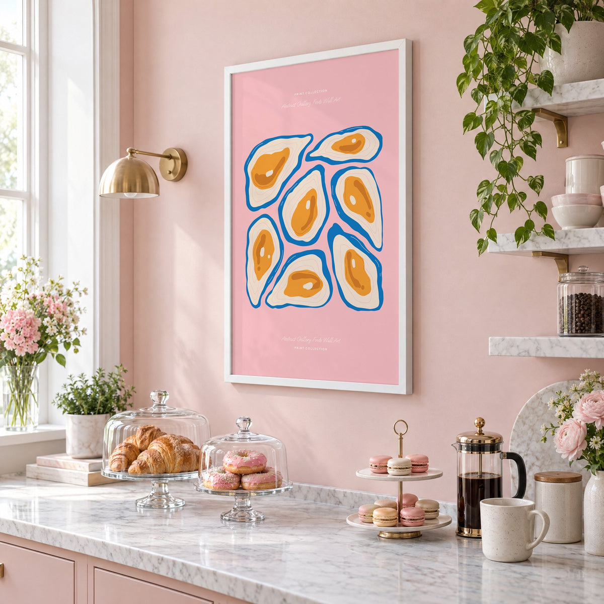 orange oysters blue shells pink print in a white frame on a blush pink wall above a patisserie counter with croissants and macarons, seen at an angle