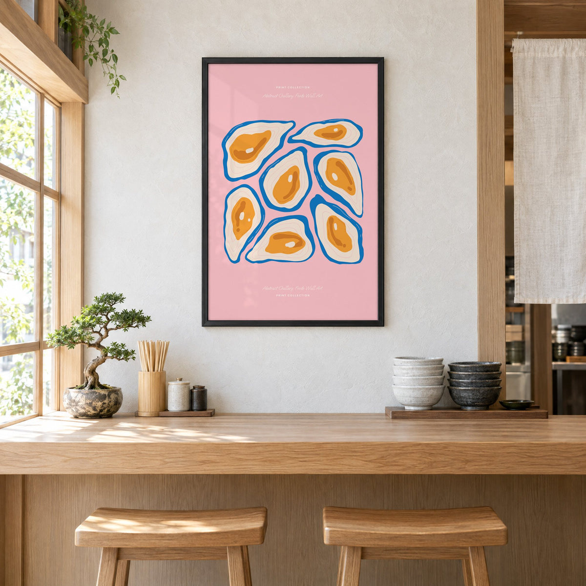 orange oysters blue shells pink print in a black frame above a light wood ramen counter with stools and stacked bowls