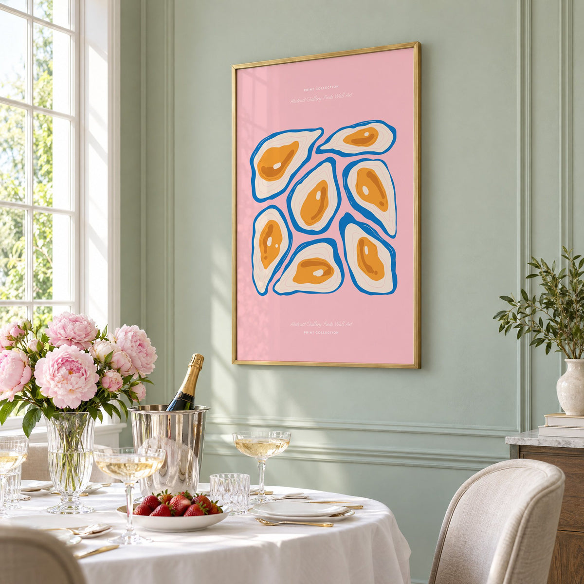 orange oysters blue shells pink print in a brass frame on a sage wall above a brunch table with champagne and peonies, seen at an angle