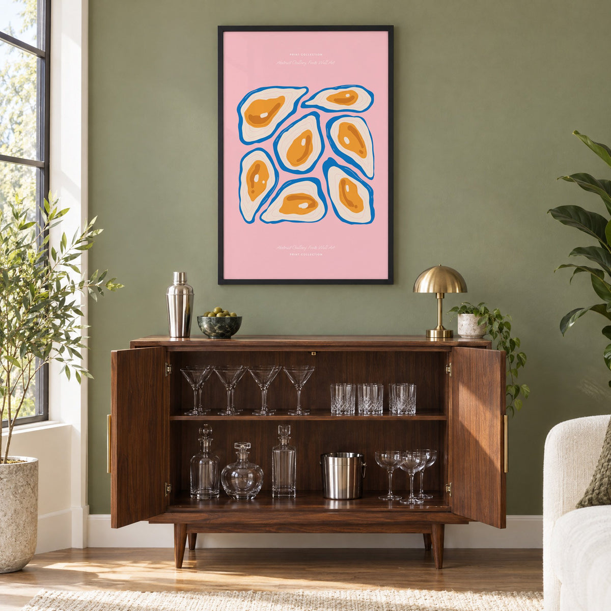 orange oysters blue shells pink print in a black frame on an olive green wall above a walnut bar cabinet with glassware