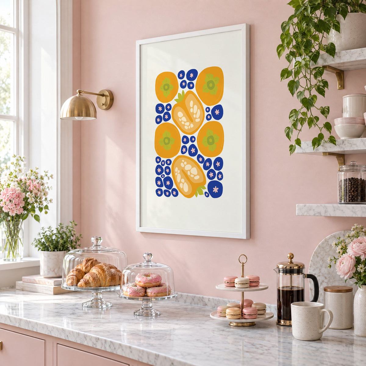 orange persimmons cobalt blueberries pattern print in a white frame on a blush pink wall above a patisserie counter with croissants and macarons, seen at an angle