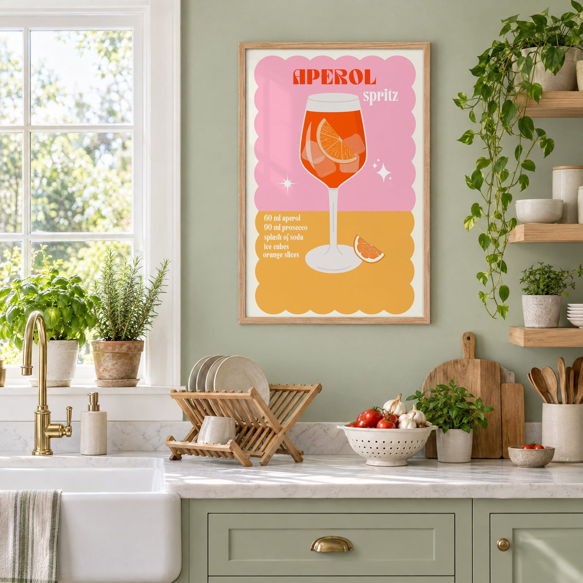 Orange spritz scalloped pink print in an oak frame on a sage green kitchen wall beside a farmhouse sink and herbs