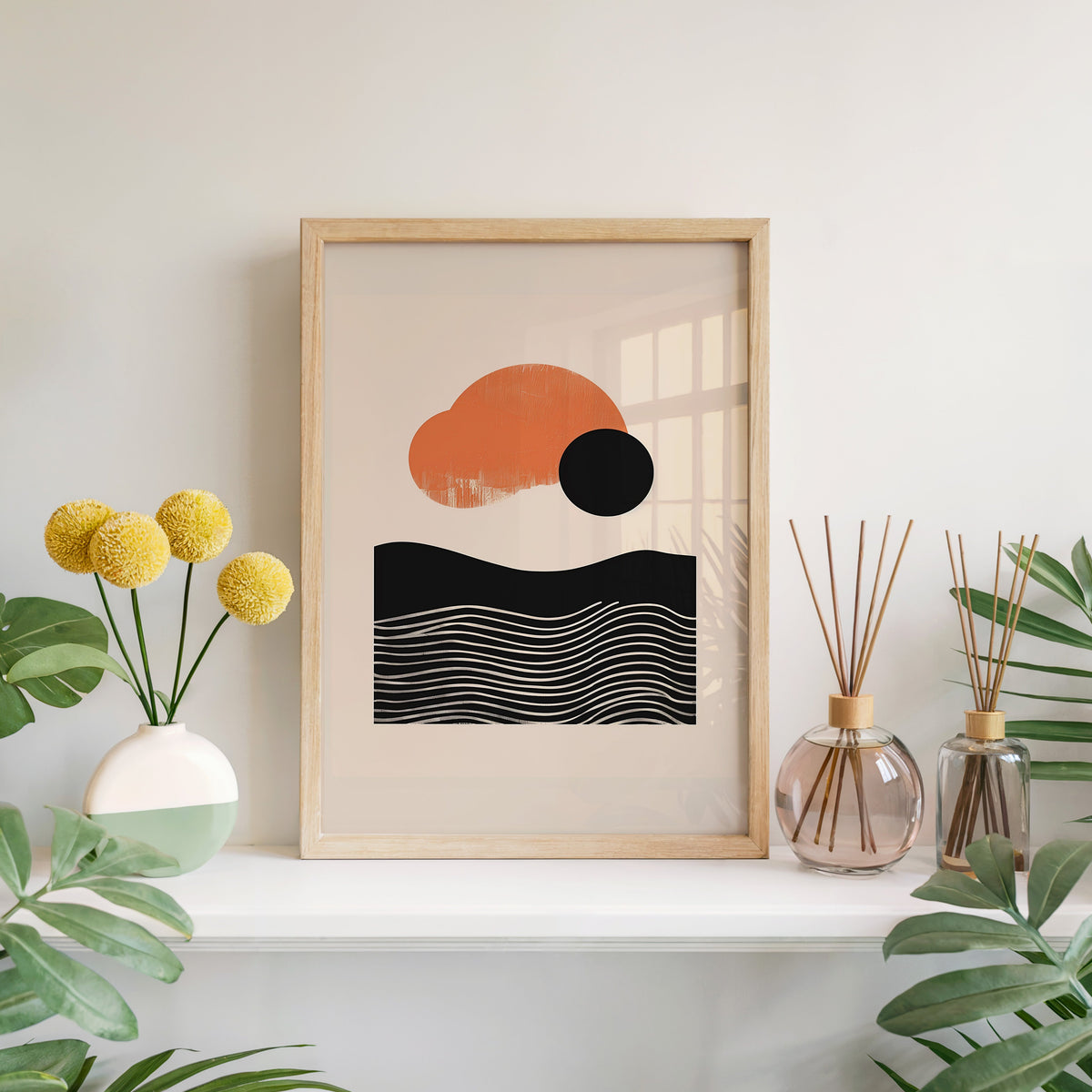 Orange sun and black wave mid century abstract print in a light oak frame leaning on a white mantel with yellow flowers