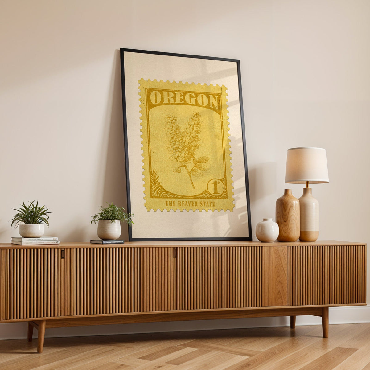 Oregon state flower print in a black frame leaning on a fluted wood credenza with vases and a lamp