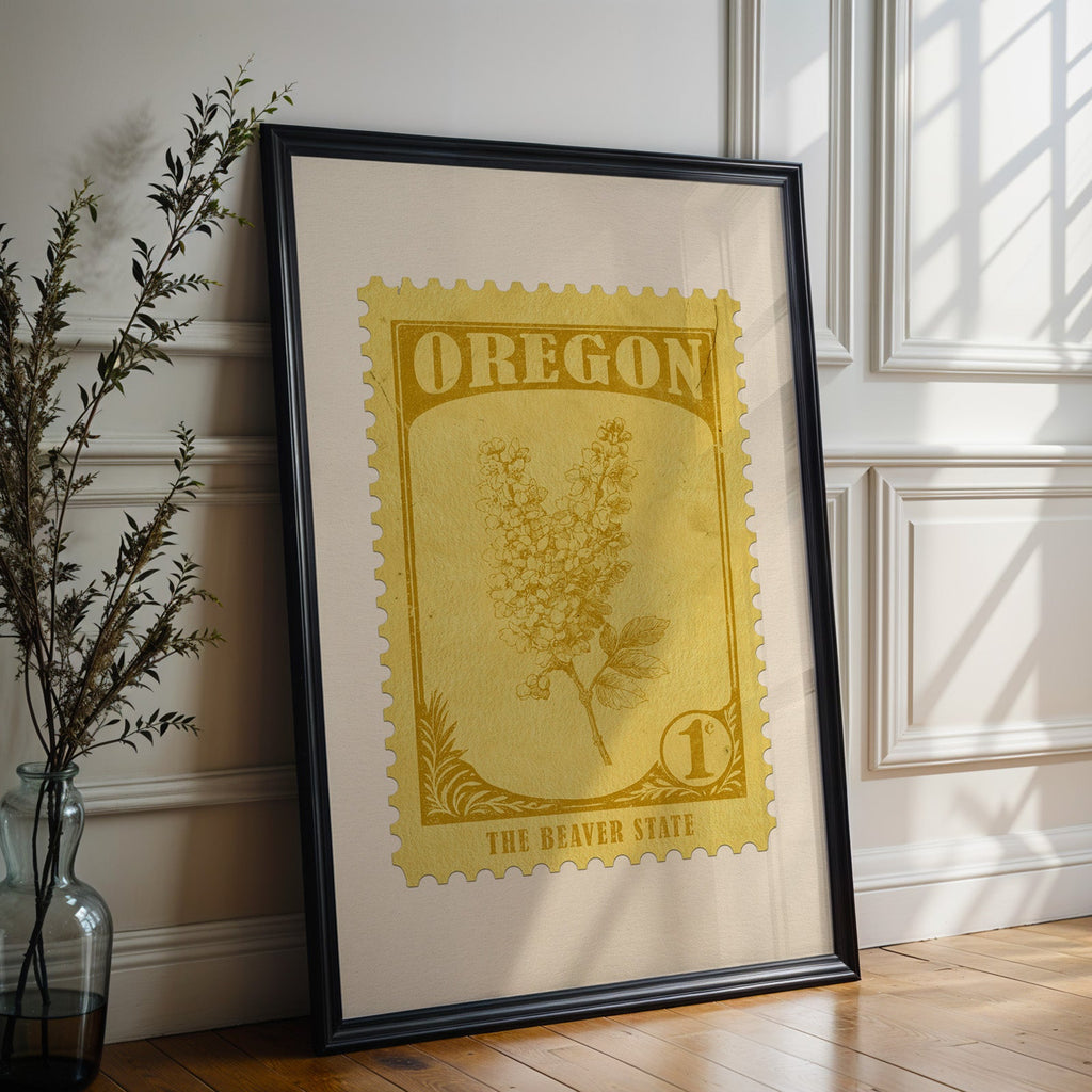 Oregon state flower print in a black frame leaning against a white panelled wall beside olive branches