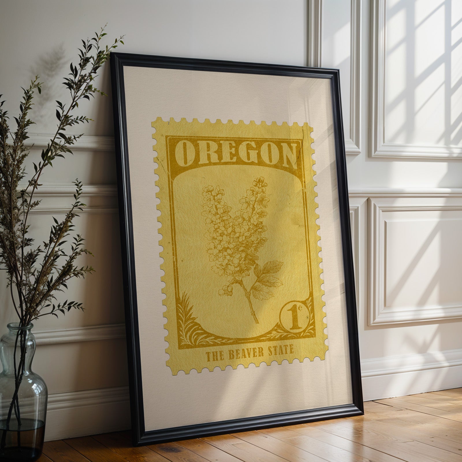 Oregon state flower print in a black frame leaning against a white panelled wall beside olive branches