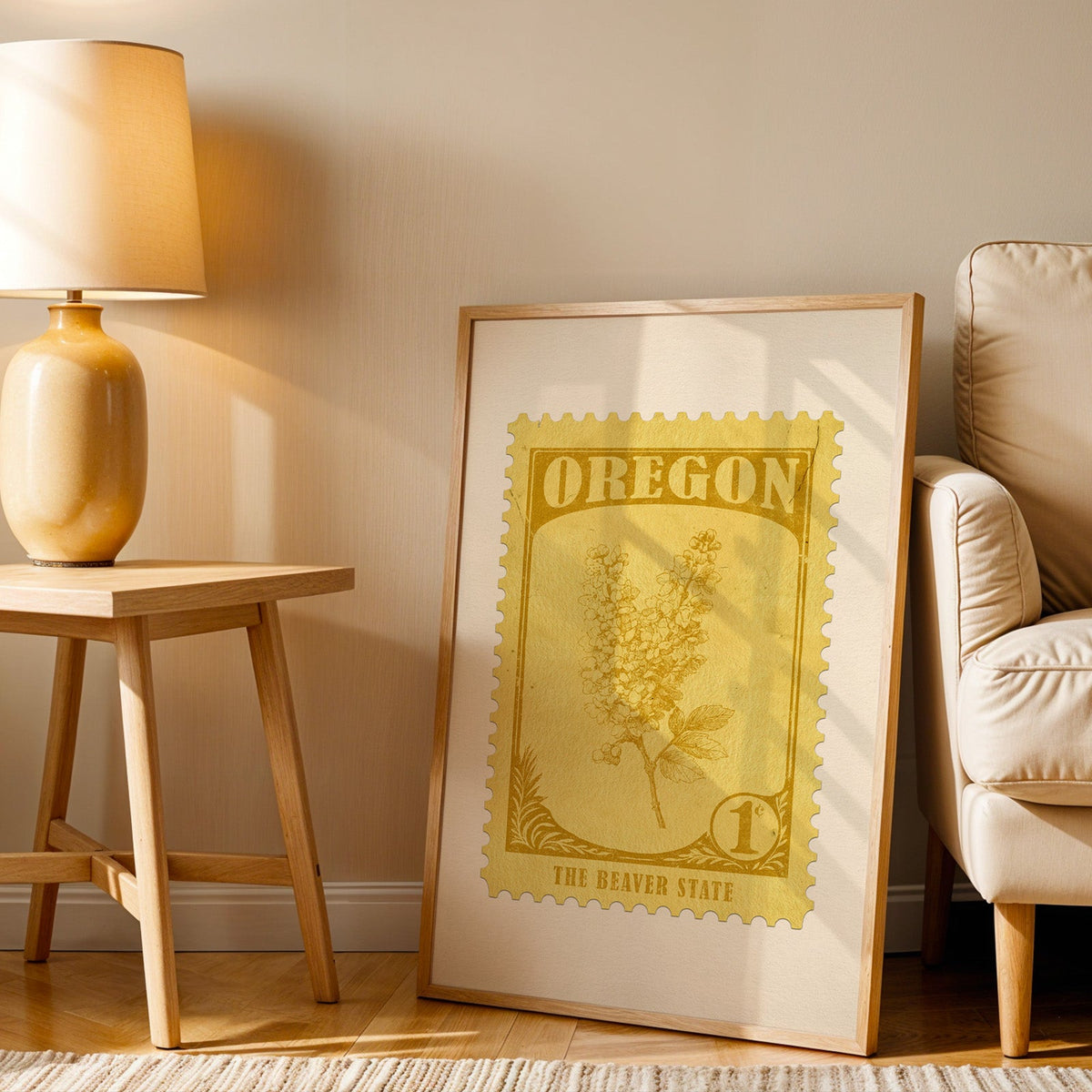 Oregon stamp print in a wood frame resting on the floor beside a beige armchair and a yellow lamp