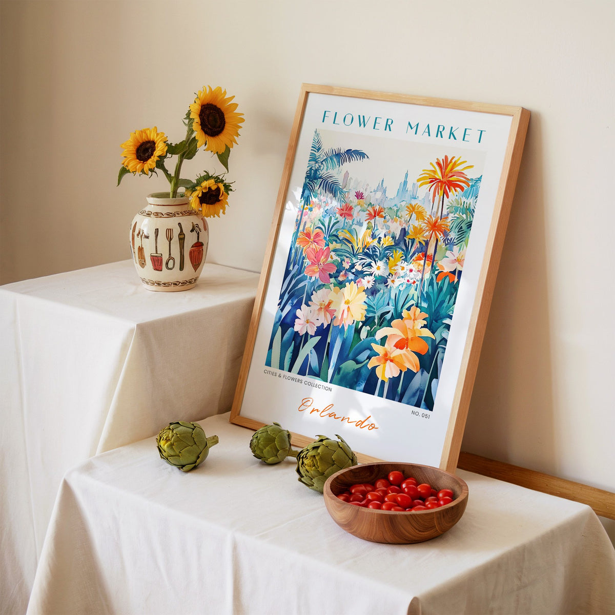 Orlando flower market print in an oak frame leaning on a linen-draped table beside a vase of sunflowers