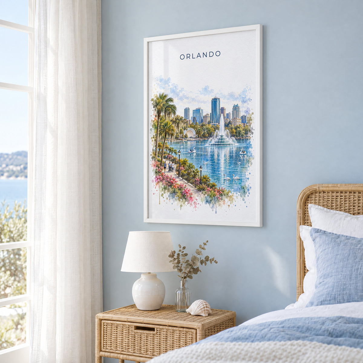 Orlando watercolor print in a white frame on a pale blue wall beside a rattan bed in a coastal bedroom