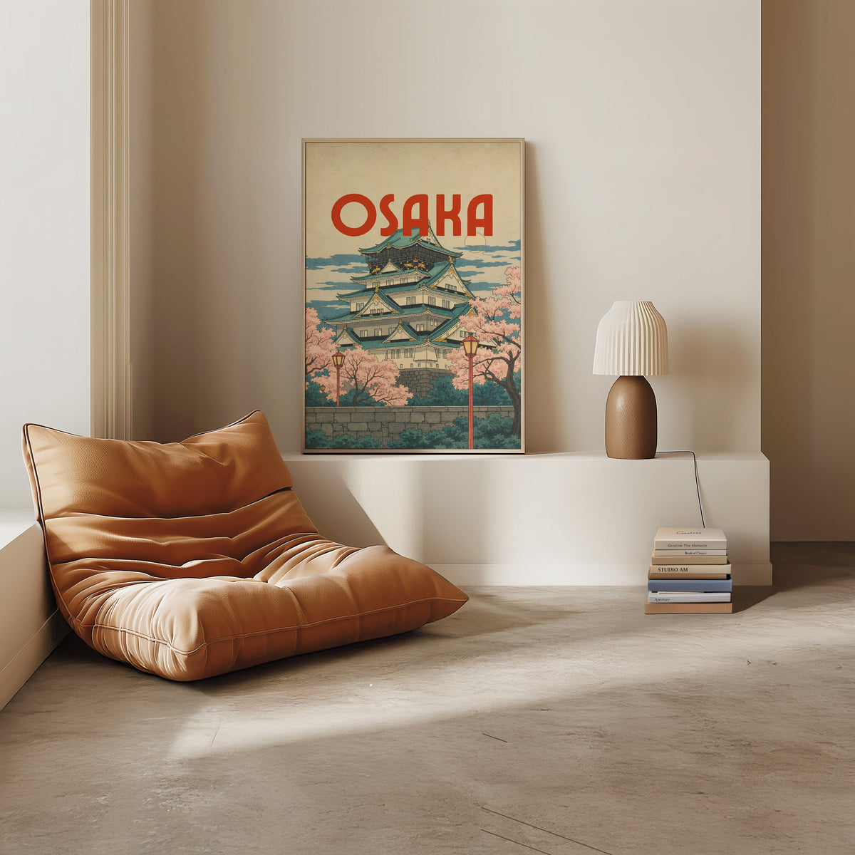Osaka Castle with teal roofs print in a light oak frame on a white ledge by a tan leather floor chair