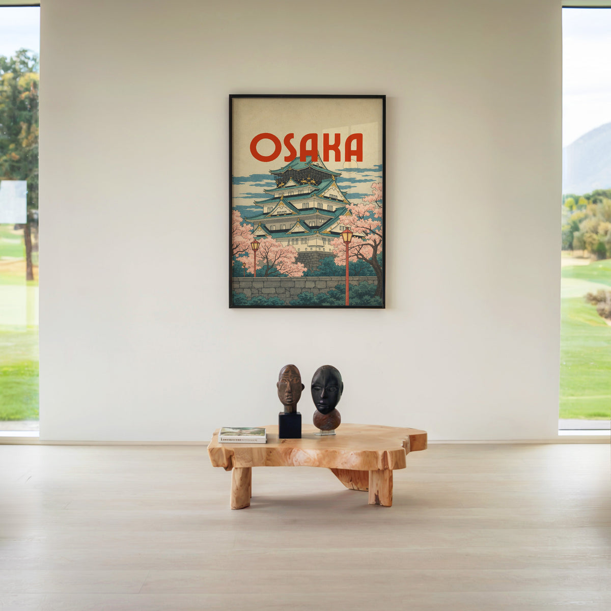 Osaka Castle with teal roofs print in a black frame above a live-edge wood coffee table between garden windows