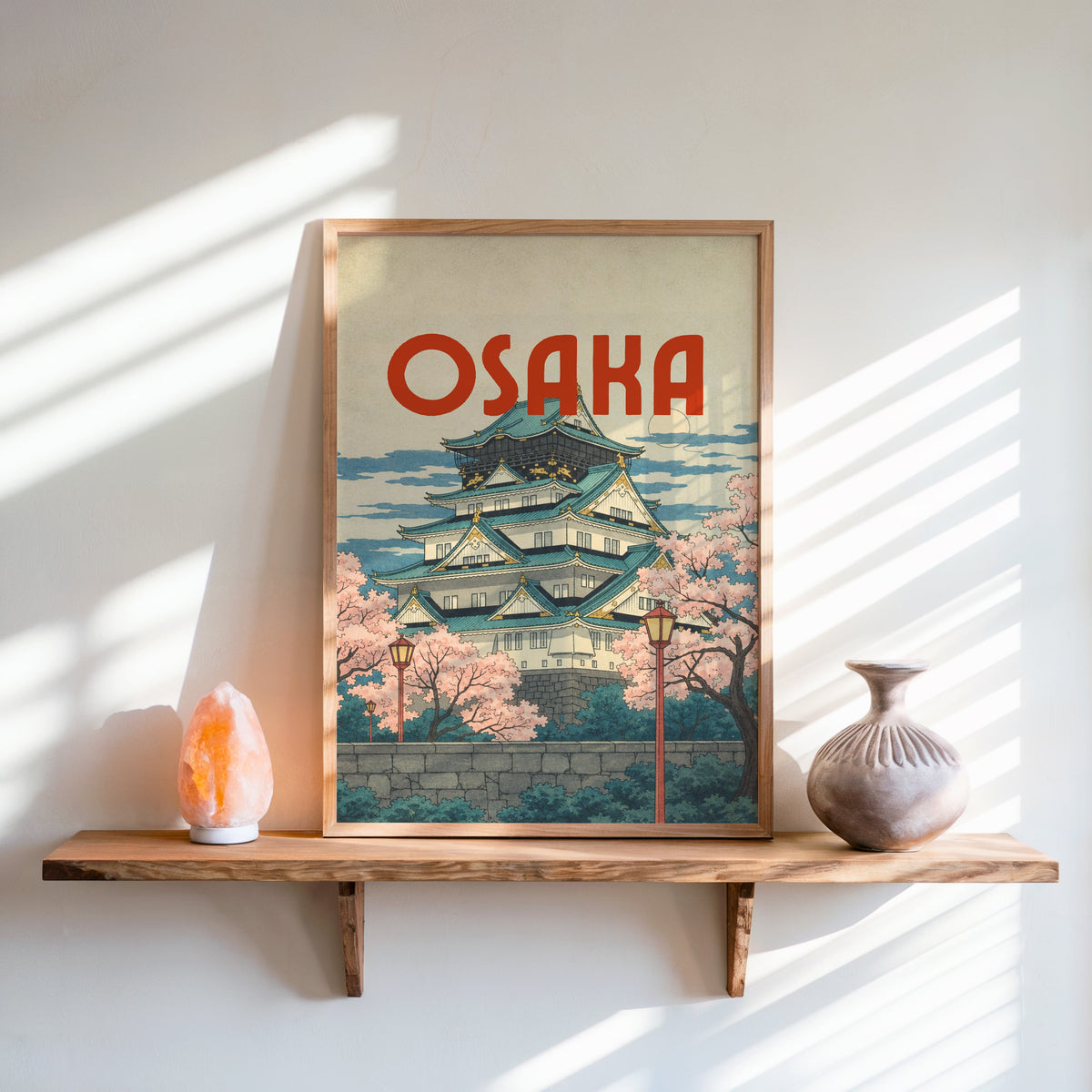 Osaka Castle with teal roofs print in an oak frame on a live-edge wall shelf with a salt lamp and clay vase