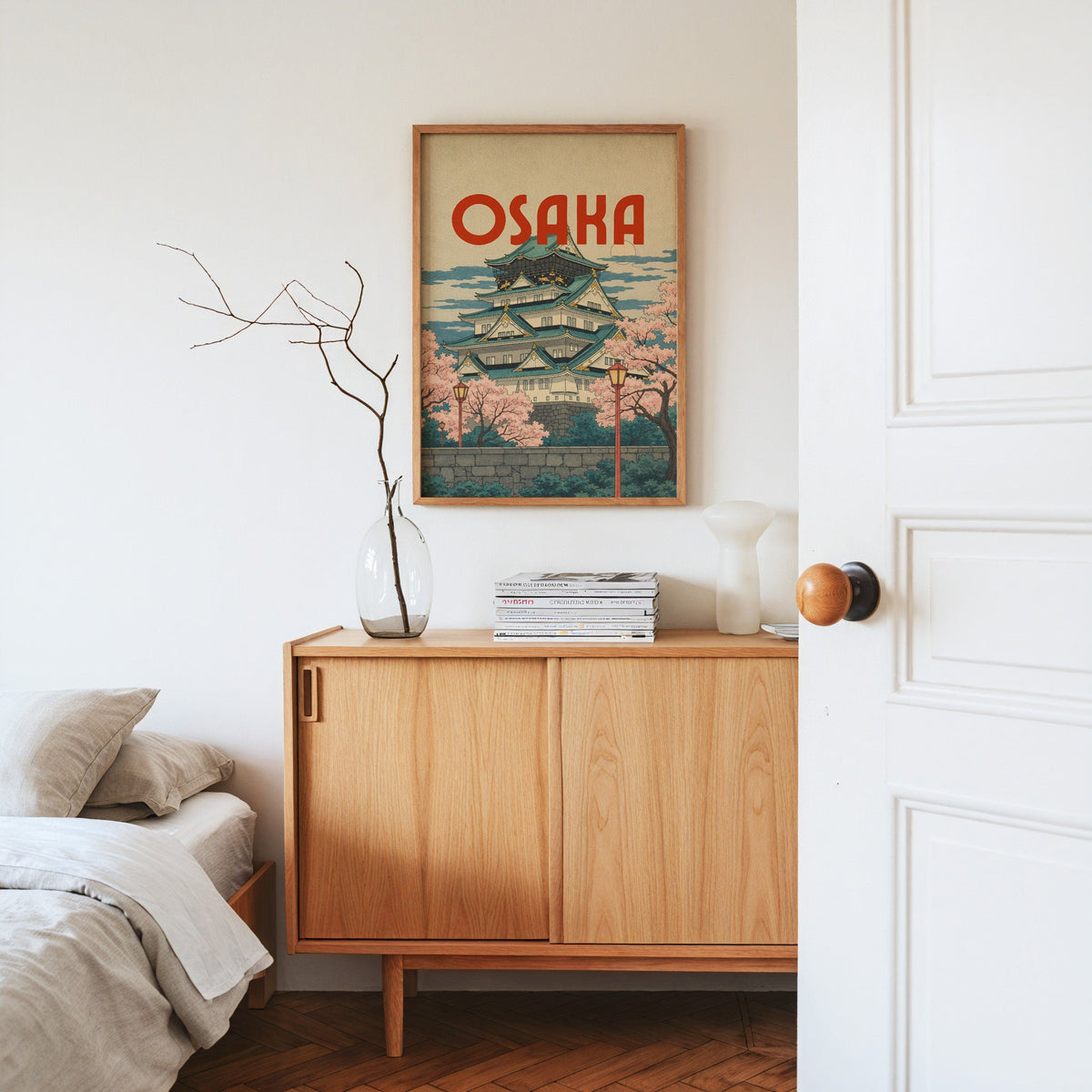 Osaka Castle with teal roofs print in an oak frame above an oak sideboard in a bedroom with linen bedding