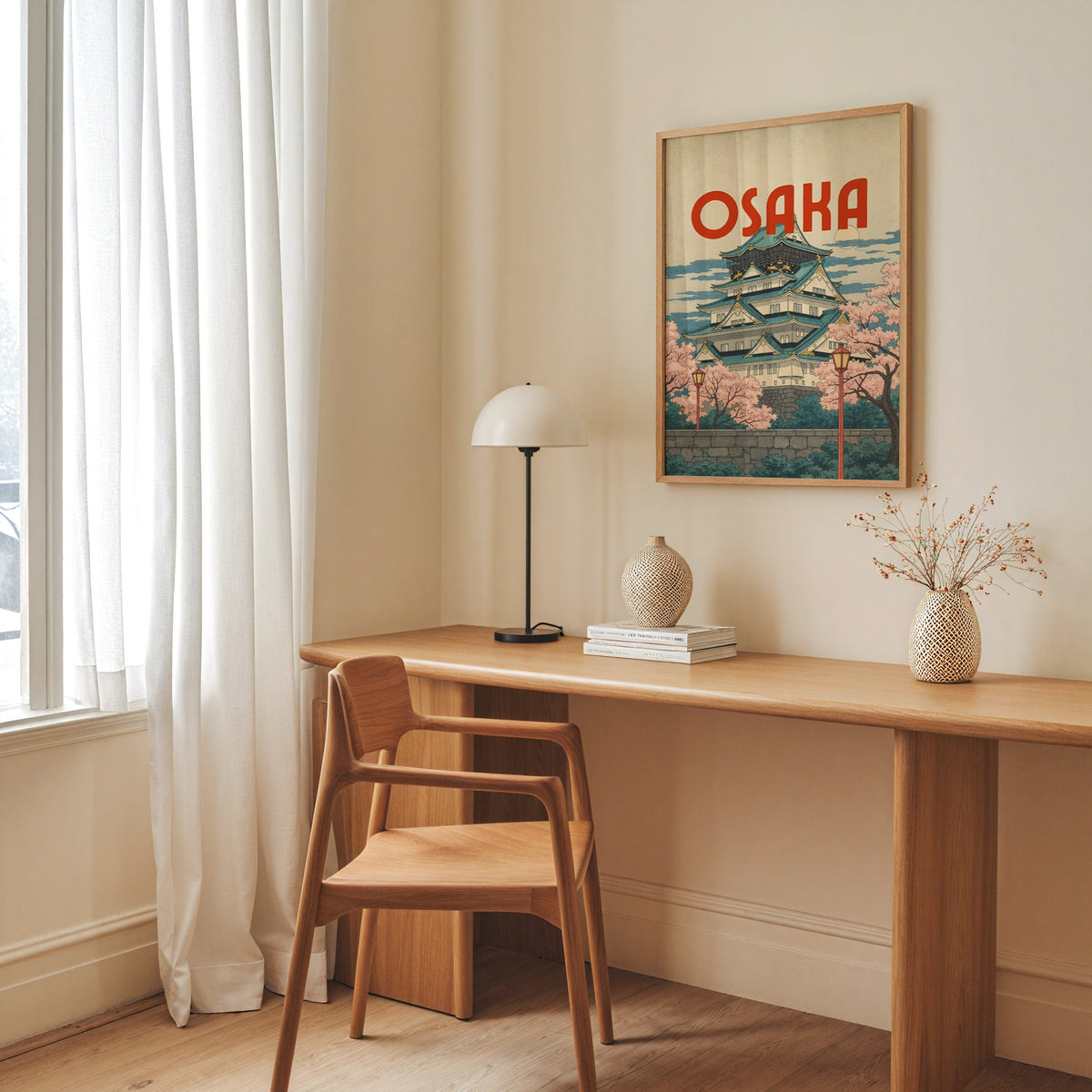 Osaka Castle with teal roofs print in an oak frame above a long oak desk with a white dome lamp and woven vases