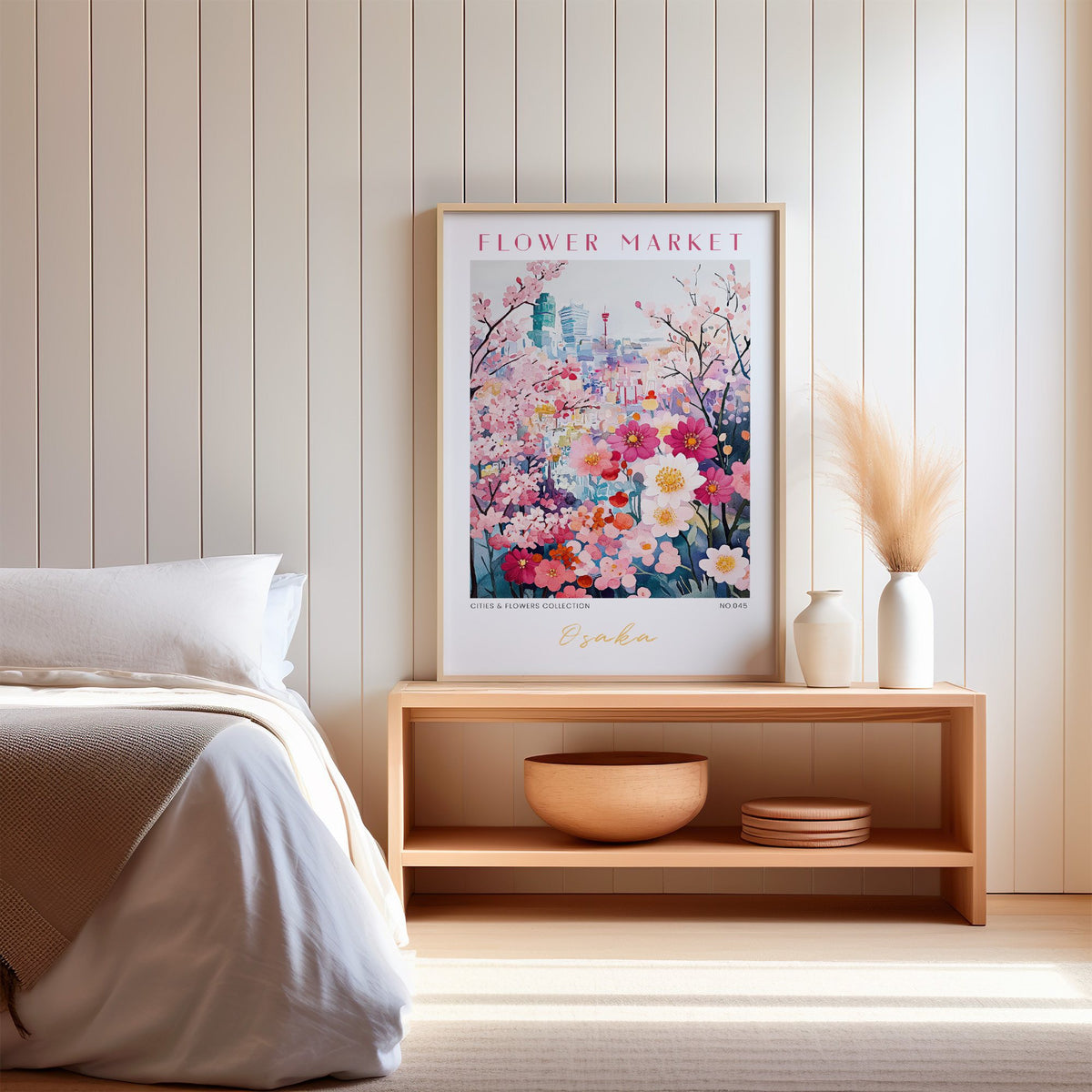 Osaka flower market print in an oak frame on a wood bench against a white shiplap bedroom wall with pampas grass