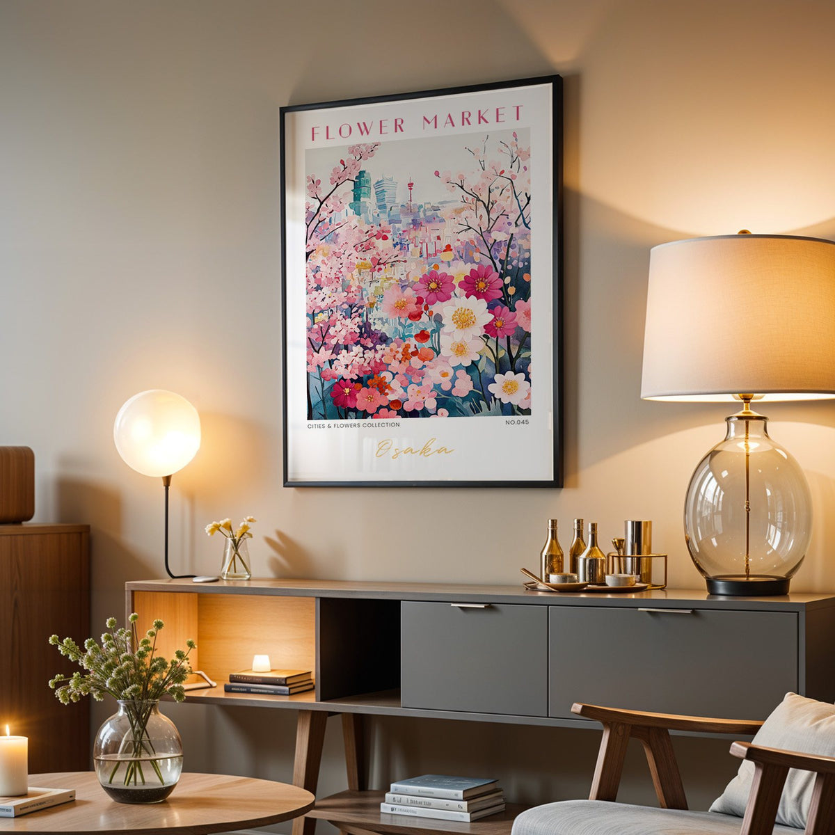 Osaka flower market print in a black frame above a grey media console with a glass table lamp