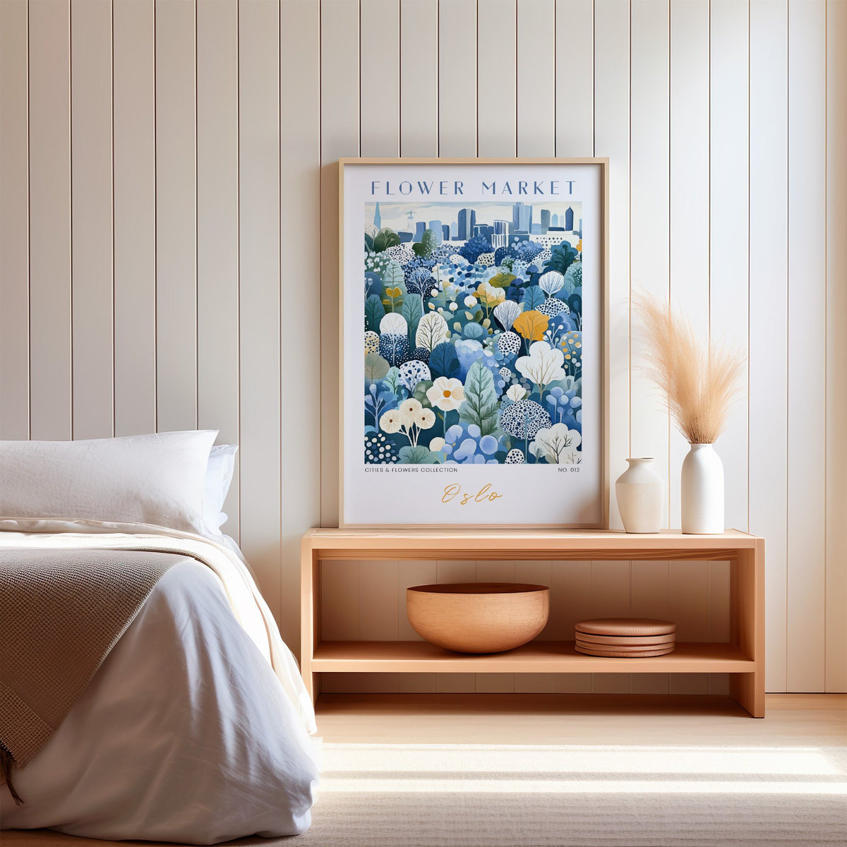 Oslo flower market print in an oak frame on a wood bench against a white shiplap bedroom wall with pampas grass