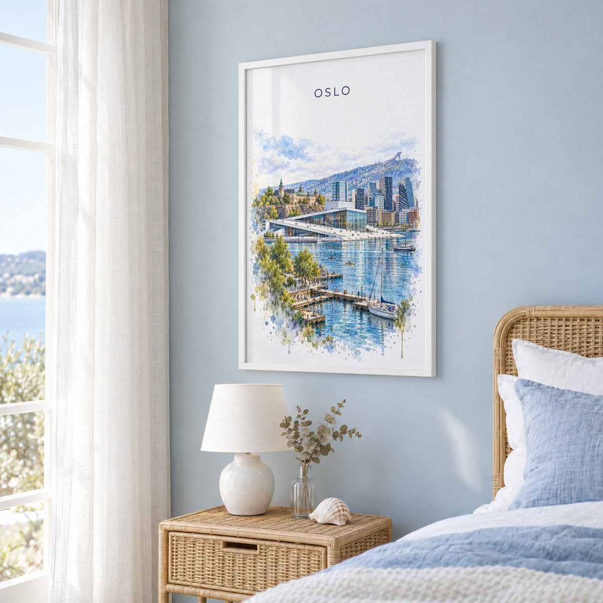 Oslo watercolor print in a white frame on a pale blue wall beside a rattan bed in a coastal bedroom