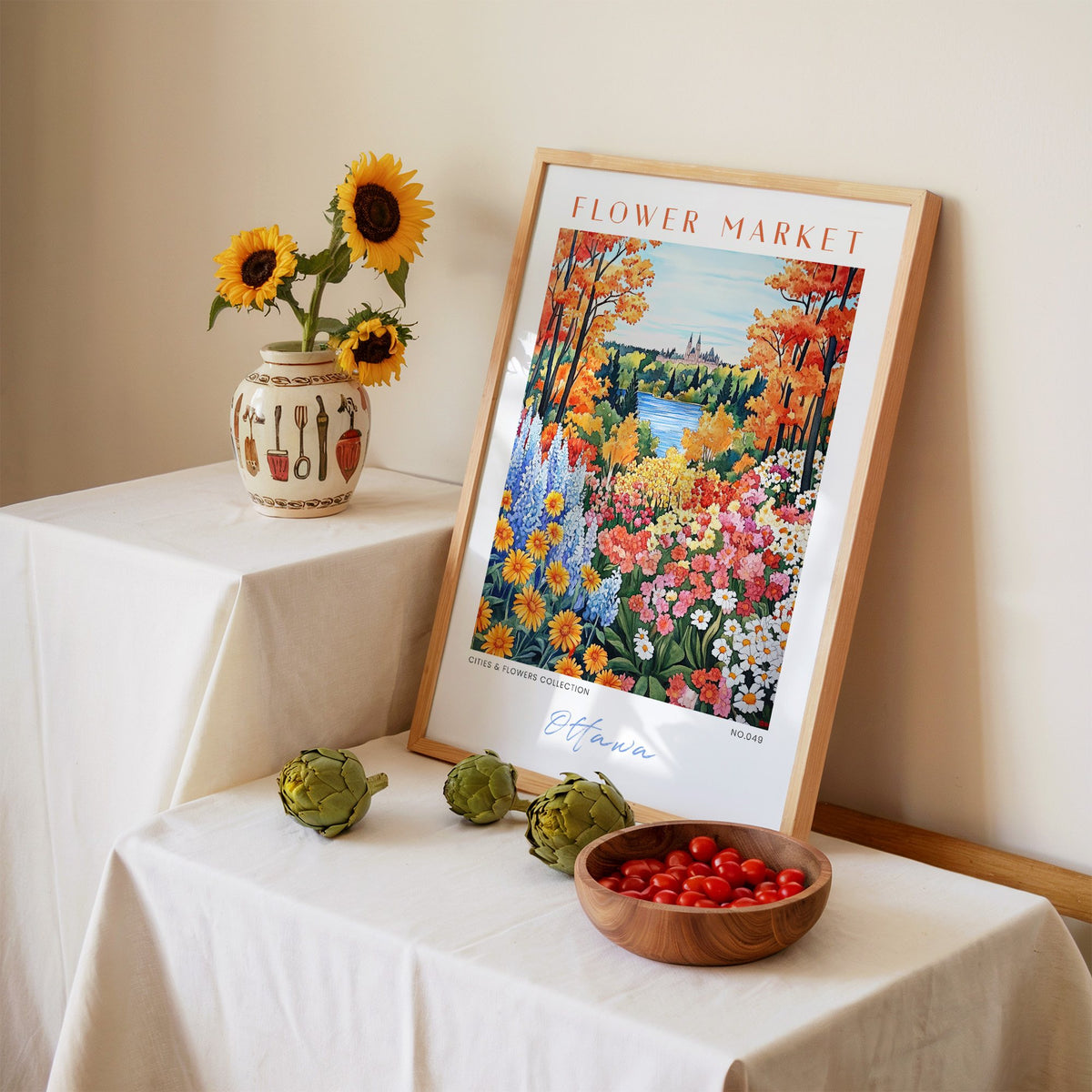 Ottawa flower market print in an oak frame leaning on a linen-draped table beside a vase of sunflowers