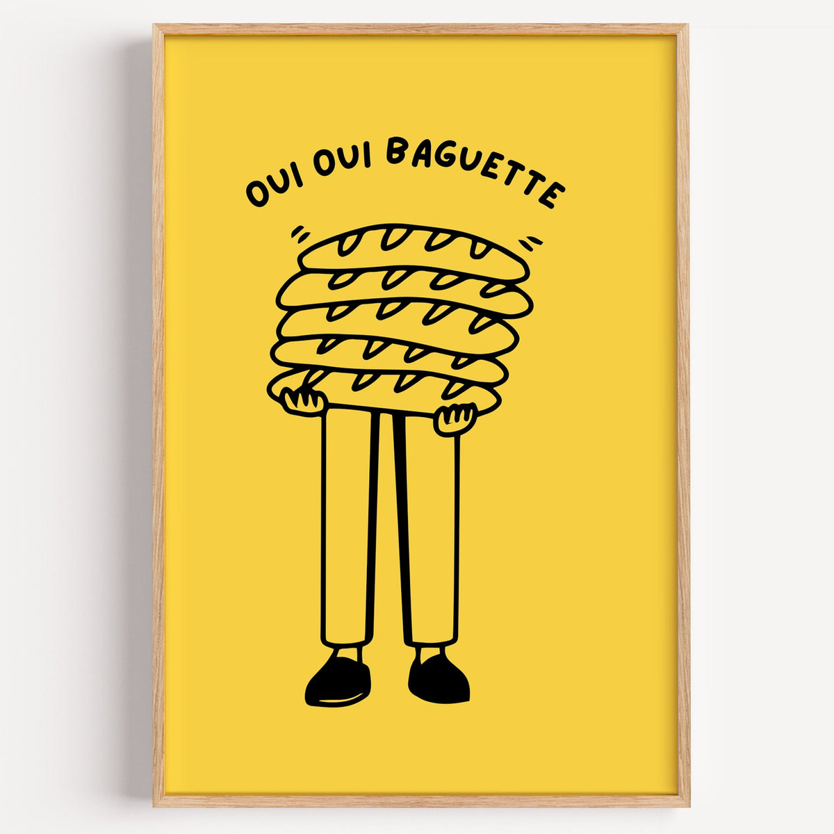 Oui Oui Baguette bakery print in a light oak frame on a plain white wall