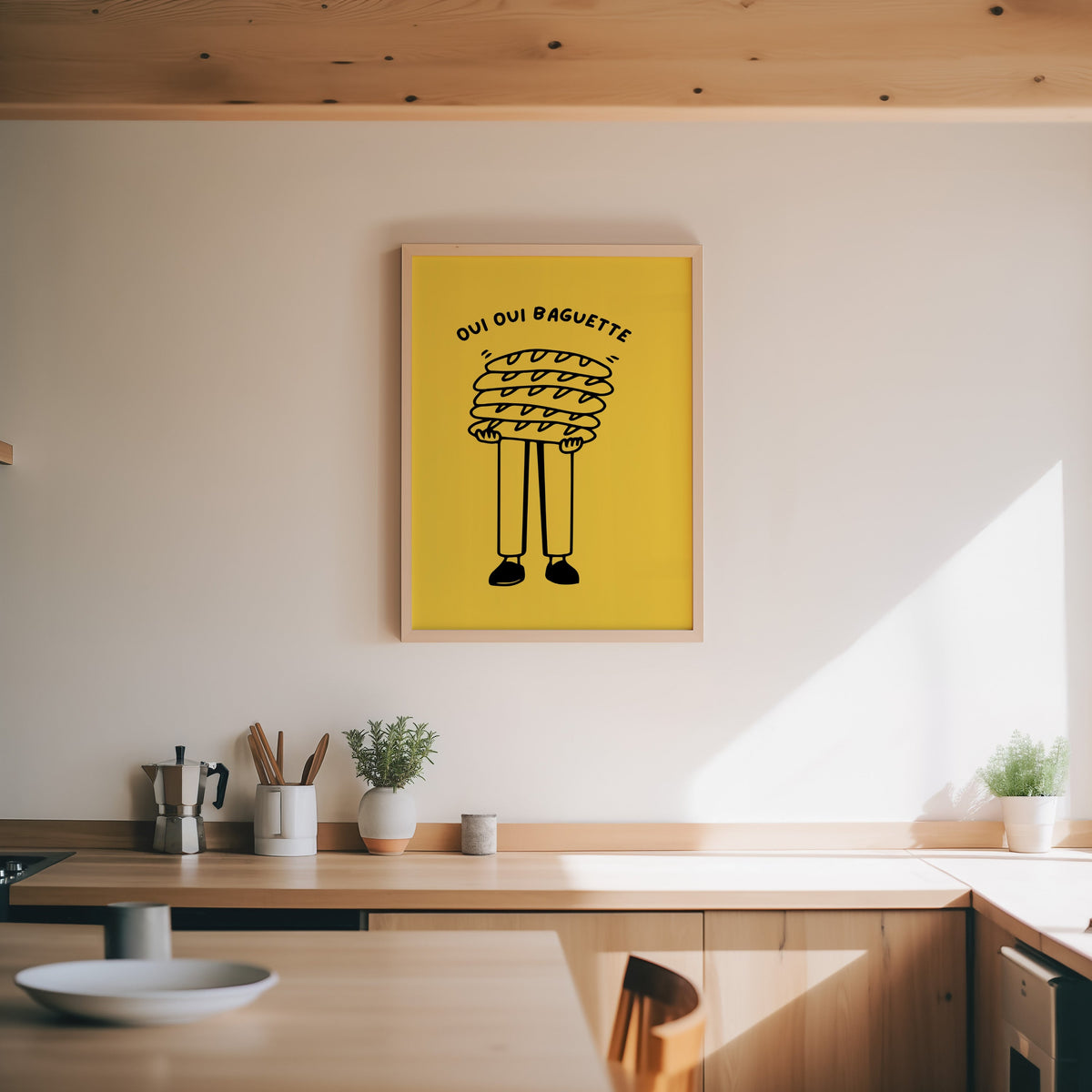 Oui Oui Baguette print in an oak frame above a wood counter with a moka pot