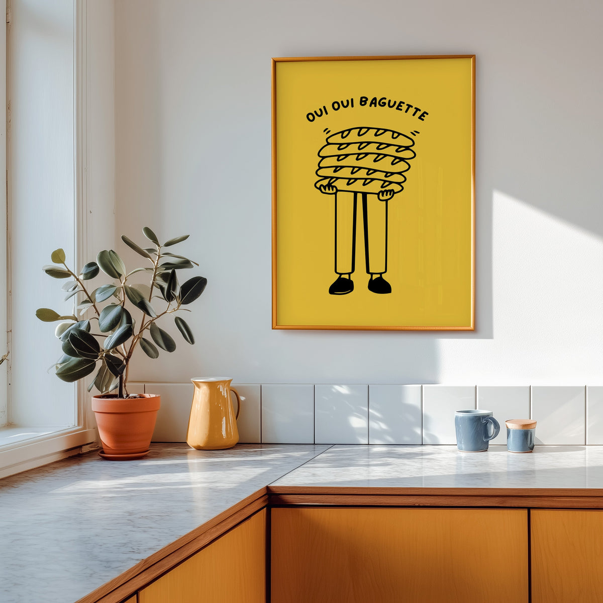 Oui Oui Baguette print in a gold frame above a marble counter with a yellow jug