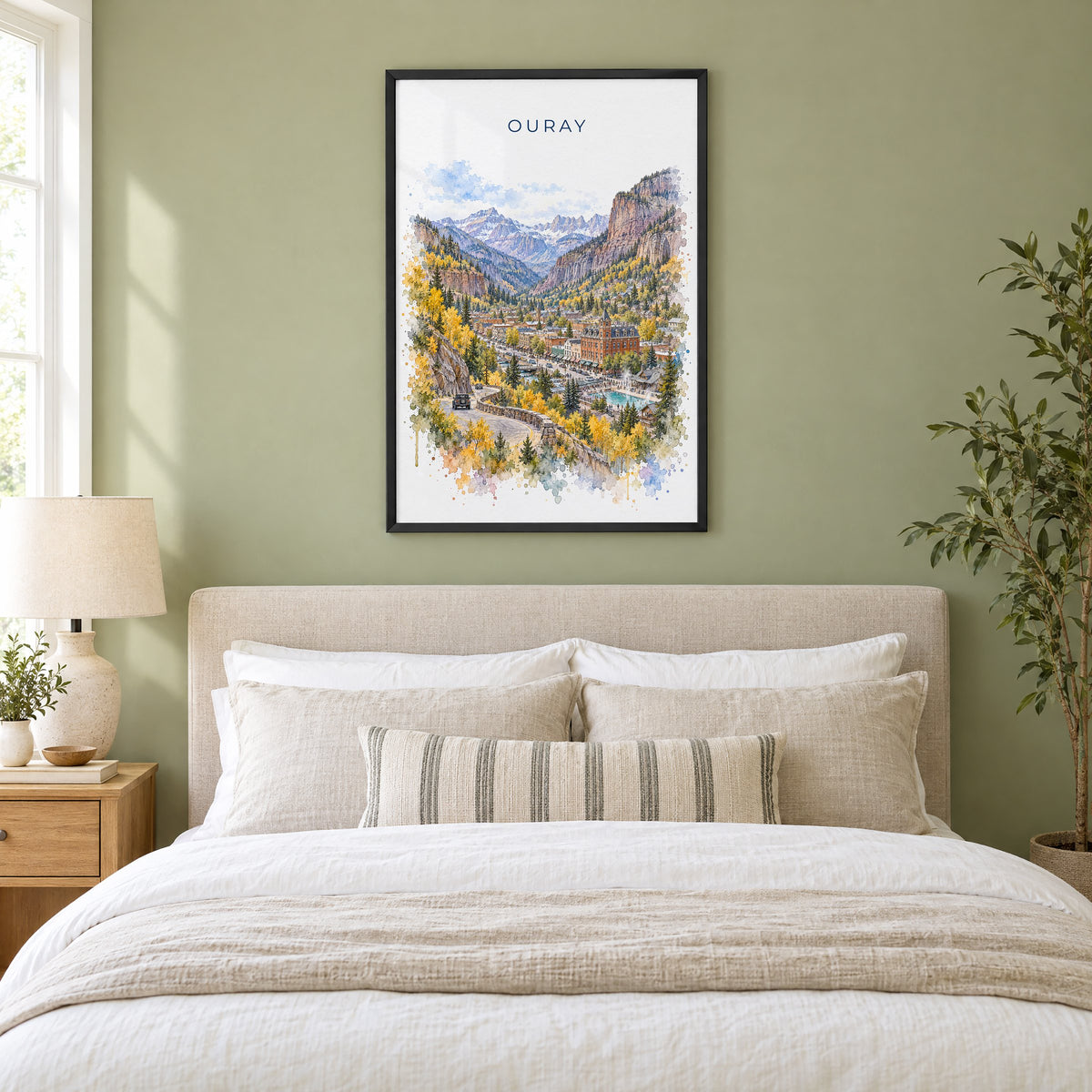 Ouray watercolor print in a black frame above an upholstered headboard in a sage green bedroom