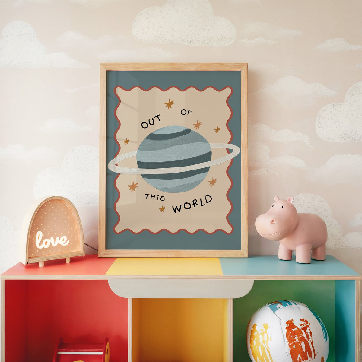 Out of this world planet nursery print in an oak frame on a rainbow toy shelf against cloud wallpaper