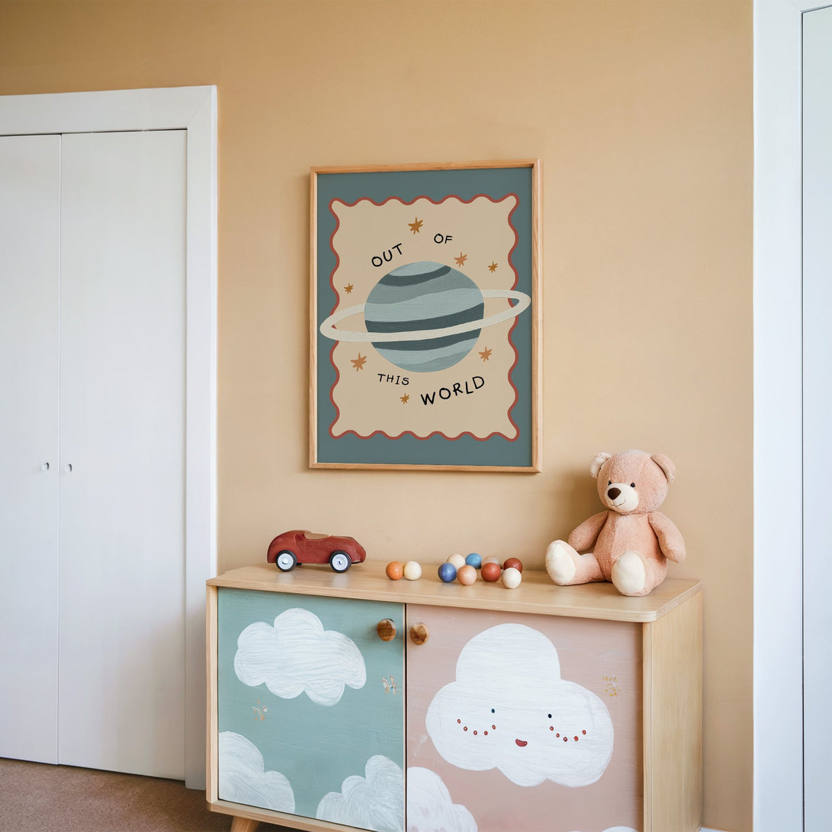 Out of this world planet nursery print in an oak frame on a peach wall above a cloud-painted cabinet