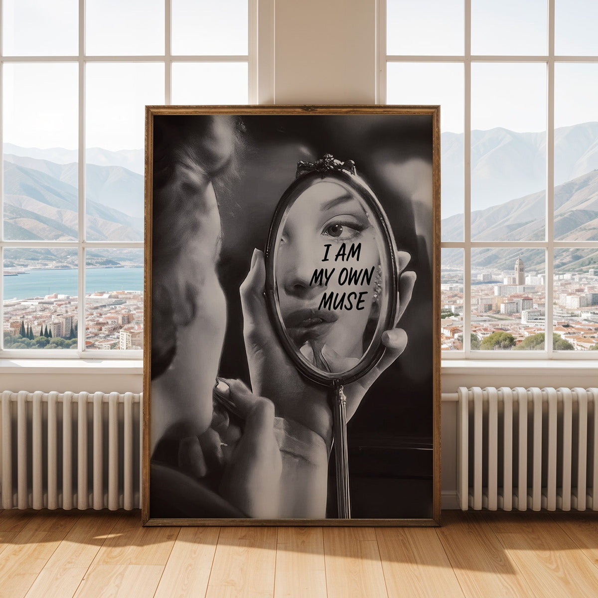I am my own muse hand mirror portrait print shown in an antique gold frame by tall windows with a sea view