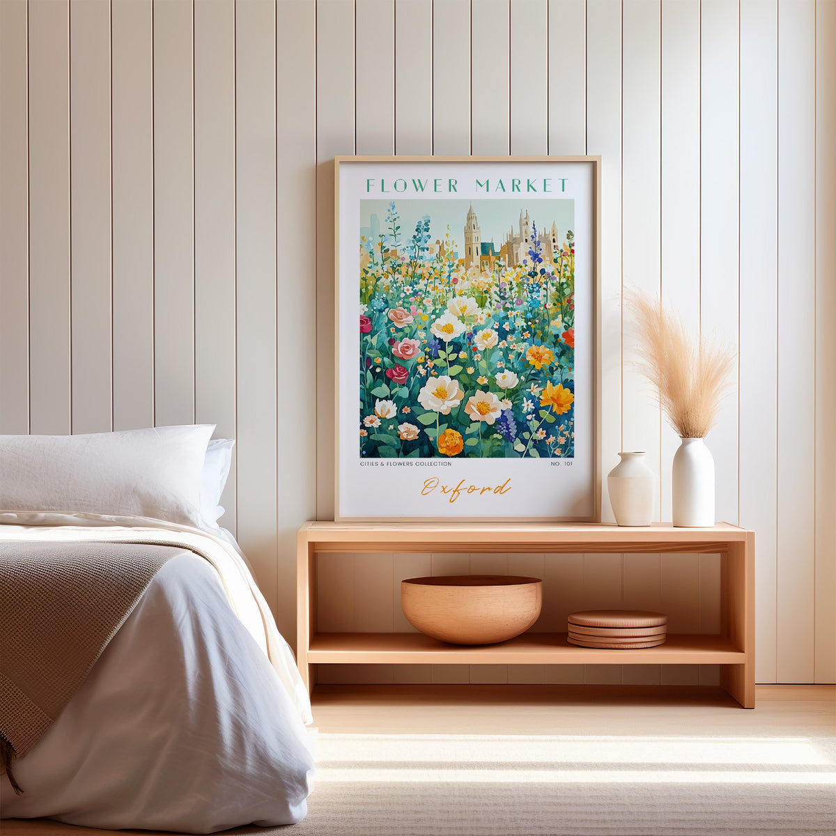Oxford flower market print in an oak frame on a wood bench against a white shiplap bedroom wall with pampas grass