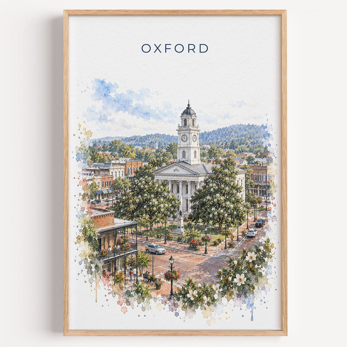 Oxford, Mississippi watercolor print in a light oak frame on a plain white wall