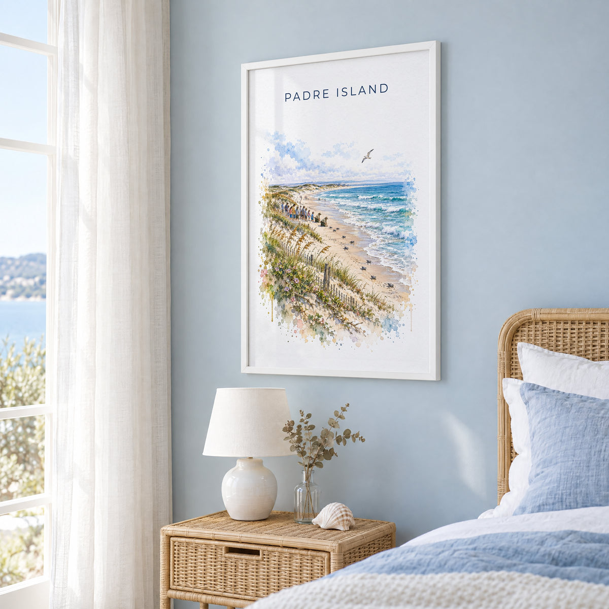 Padre Island National Seashore watercolor print in a white frame on a pale blue wall beside a rattan bed in a coastal bedroom