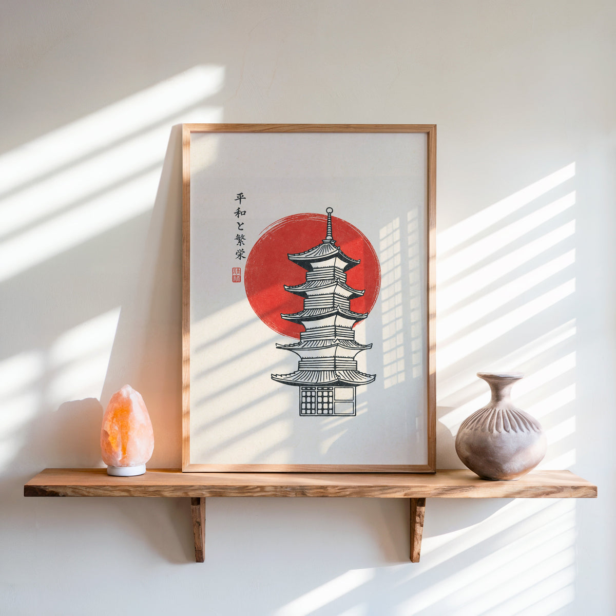 pagoda line art with red sun print in an oak frame on a live-edge wall shelf with a salt lamp and clay vase