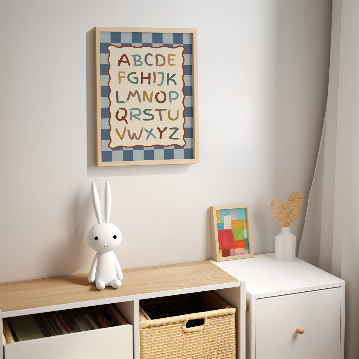 Painted alphabet wavy frame nursery print in an oak frame above a kids cubby shelf with a woven basket and bunny lamp