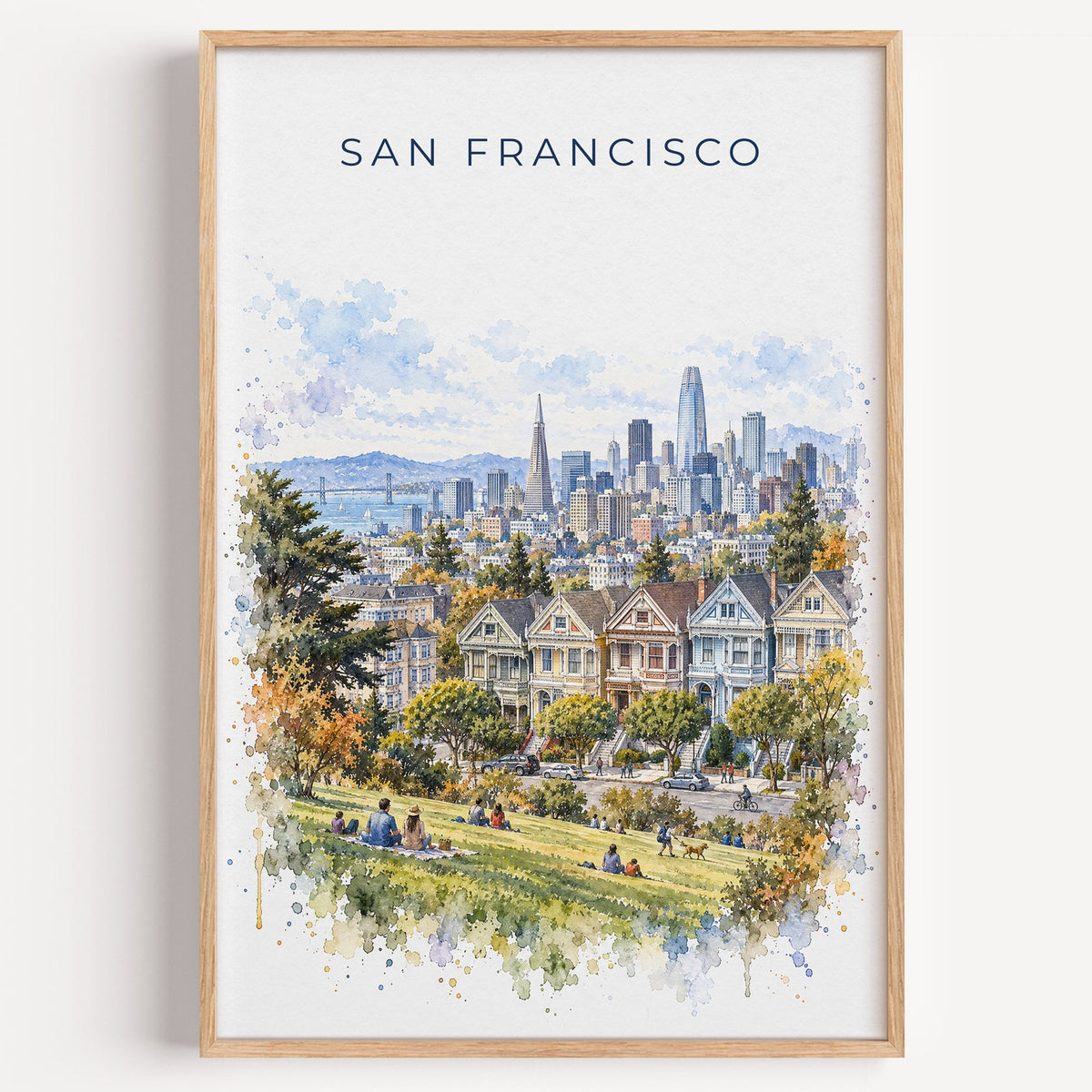 Painted Ladies San Francisco watercolor print in a light oak frame on a plain white wall