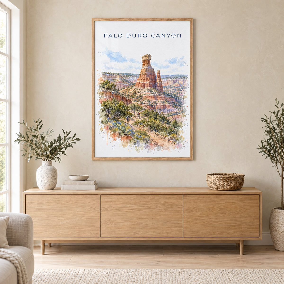 Palo Duro Canyon watercolor print in an oak frame above a light wood sideboard in a Scandinavian living room