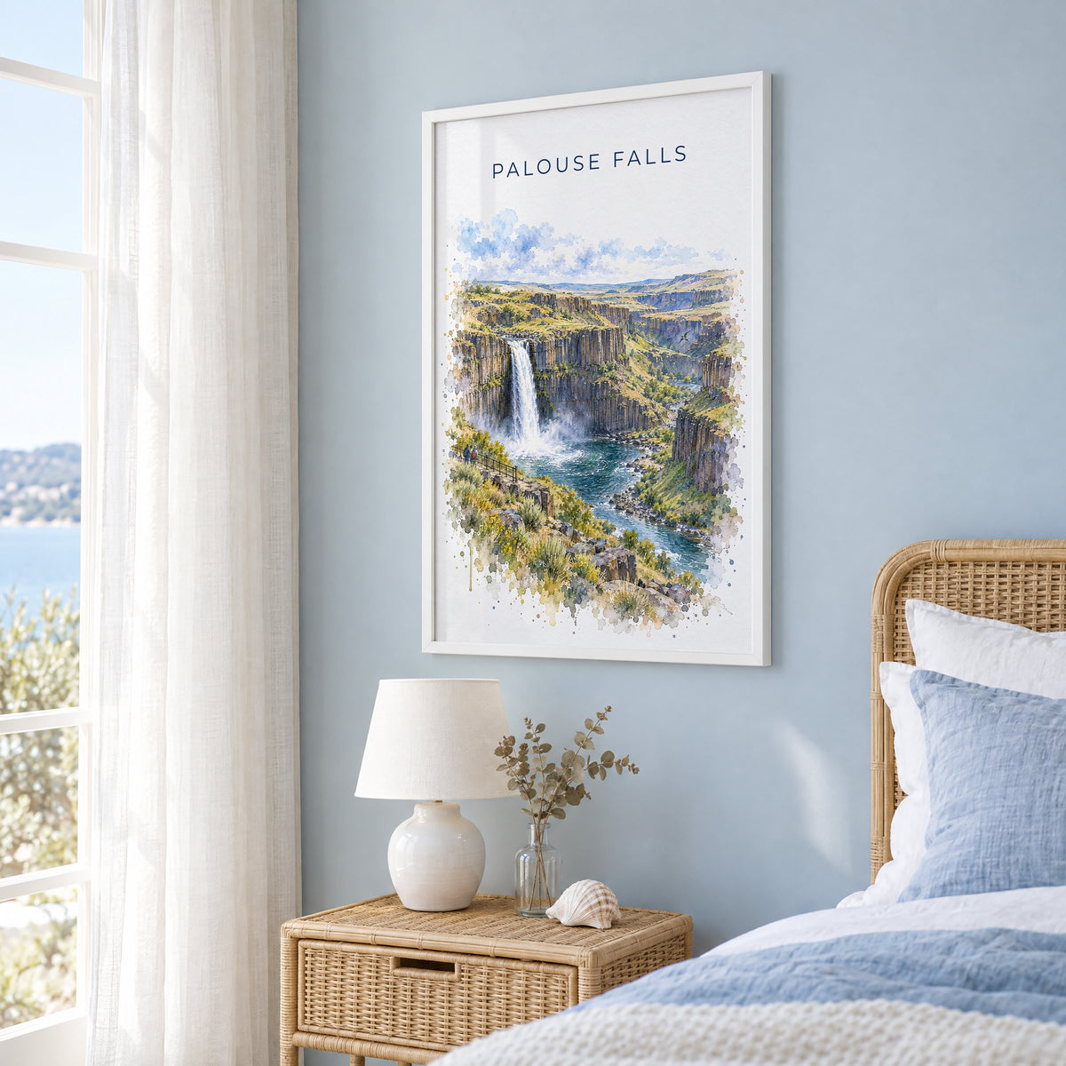 Palouse Falls watercolor print in a white frame on a pale blue wall beside a rattan bed in a coastal bedroom