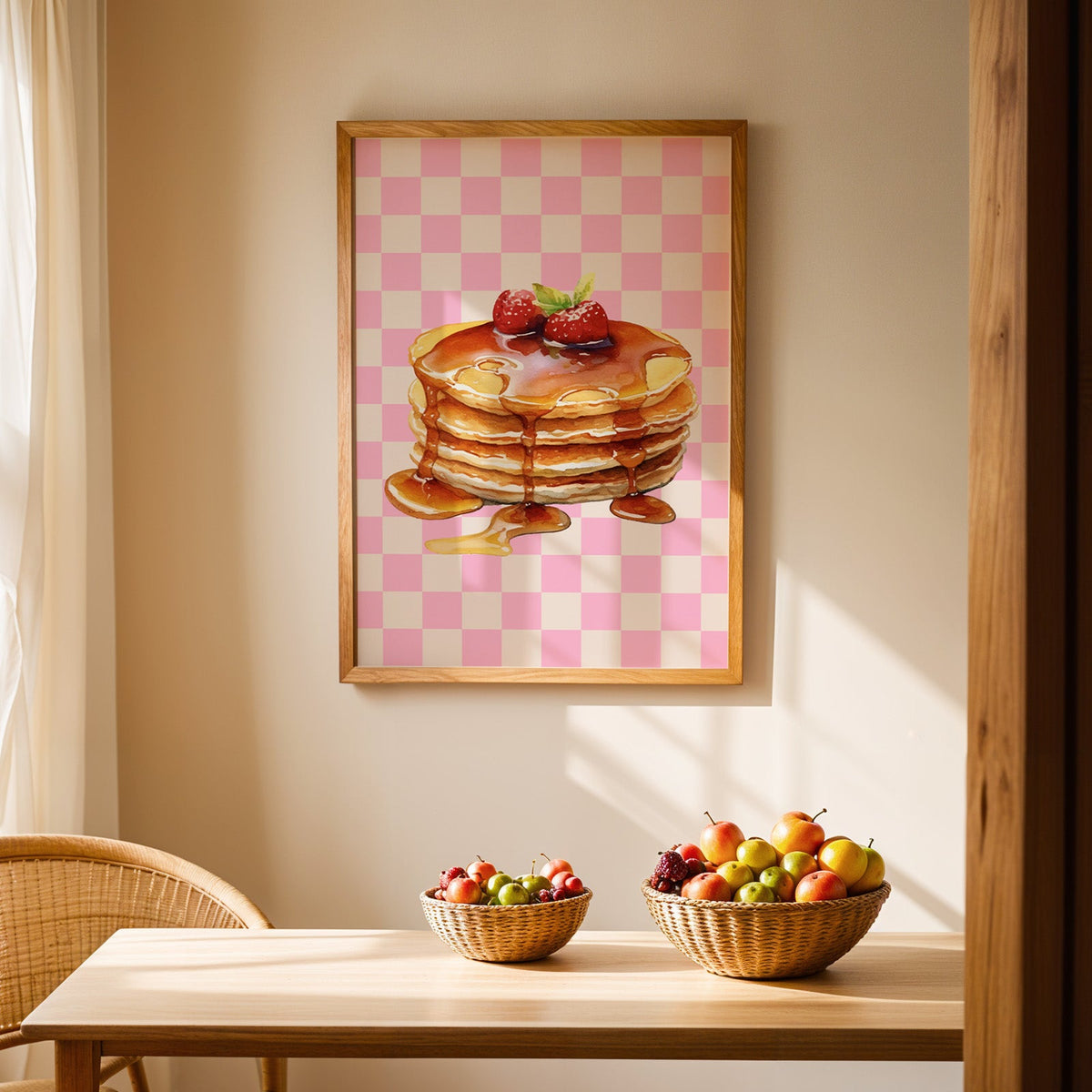Pancake stack pink check print in an oak frame above a light wood dining table with baskets of fruit