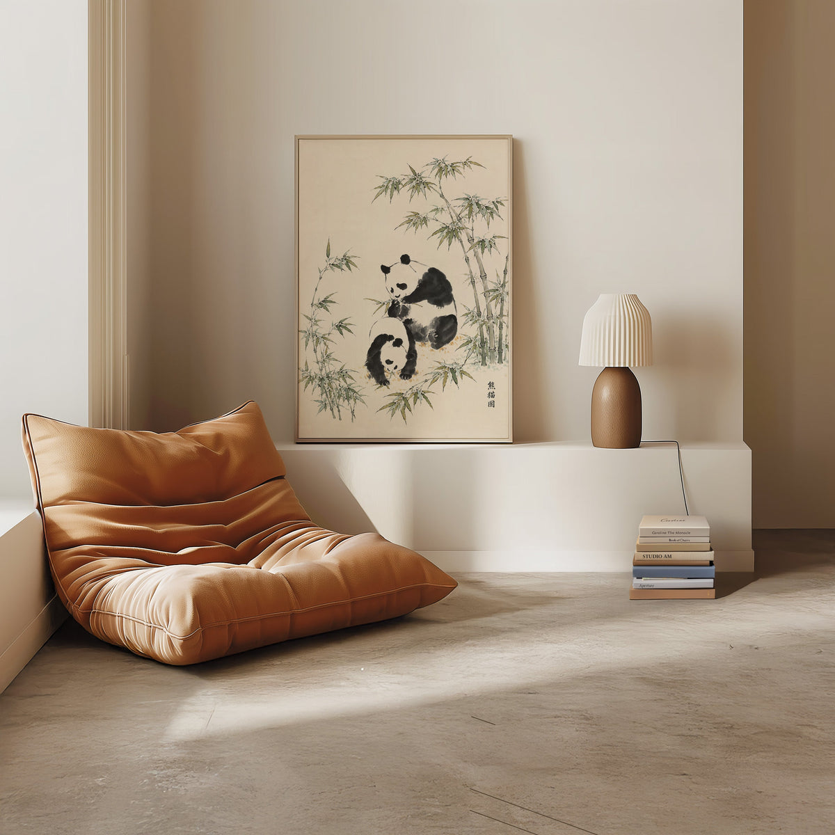 two pandas with bamboo ink painting print in a light oak frame on a white ledge by a tan leather floor chair