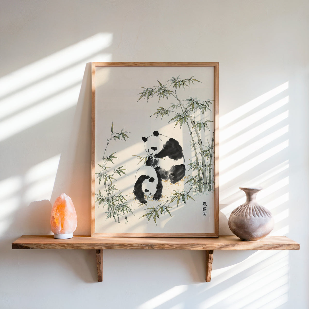 two pandas with bamboo ink painting print in an oak frame on a live-edge wall shelf with a salt lamp and clay vase