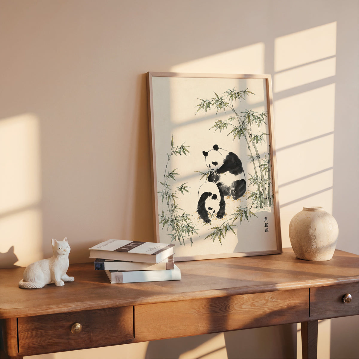 two pandas with bamboo ink painting print shown in a rose gold frame leaning on a wooden writing desk with books