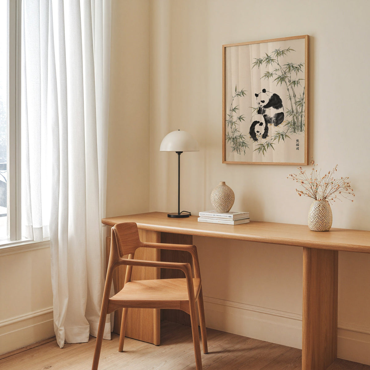 two pandas with bamboo ink painting print in an oak frame above a long oak desk with a white dome lamp and woven vases