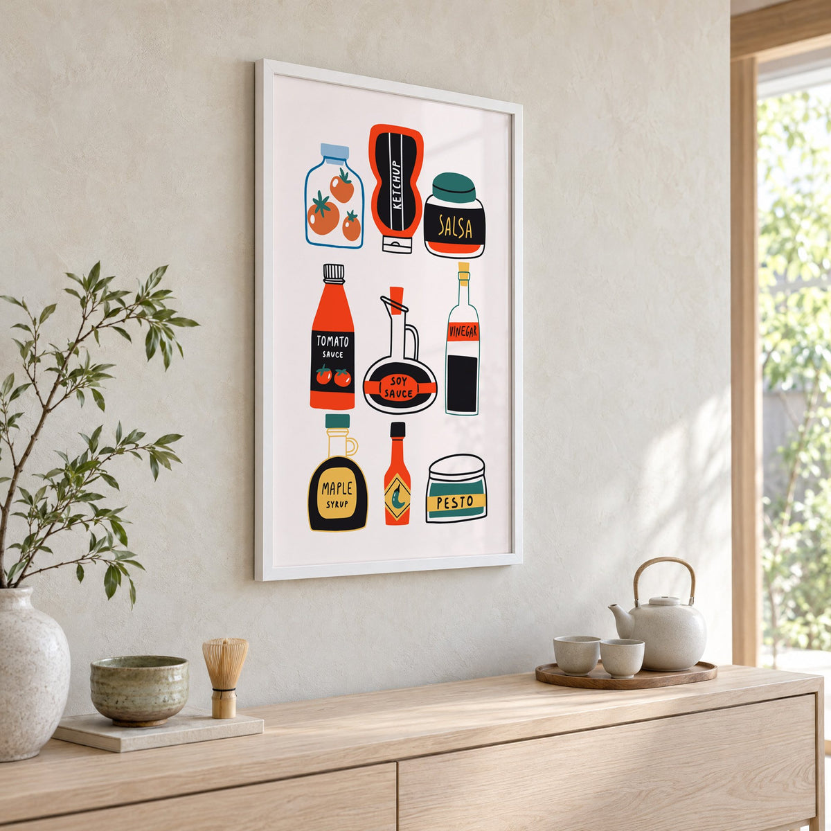 Pantry sauces bottles and jars print in a white frame above a pale wood console with a matcha tea set
